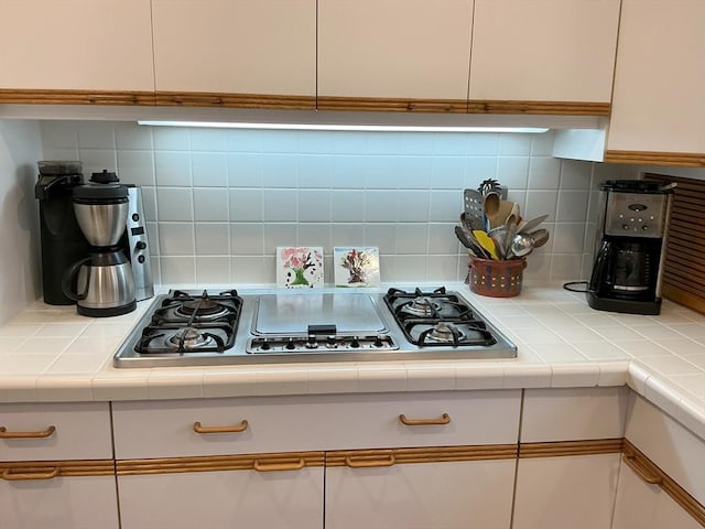 kitchen featuring decorative backsplash, white cabinetry, stainless steel gas cooktop, and tile countertops