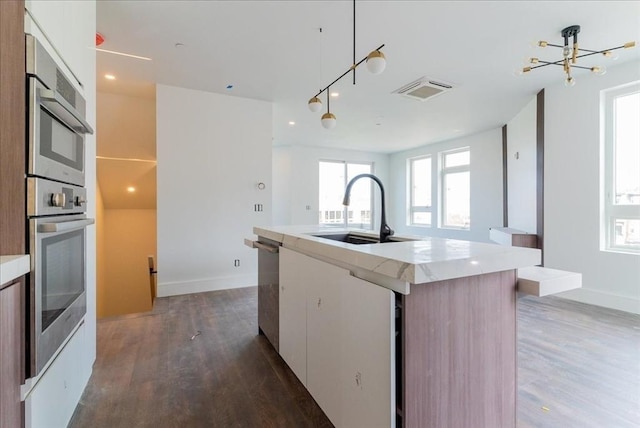 29 Woodford St Unit 2, Boston, MA 02125 - kitchen with a sink, wood finished floors, an island with sink, stainless steel appliances, and baseboards