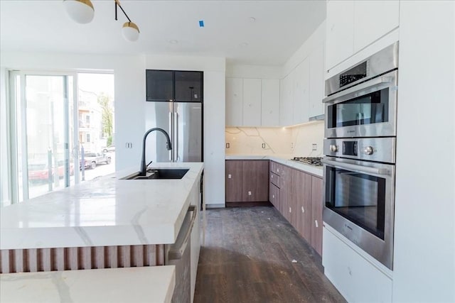 29 Woodford St Unit 2, Boston, MA 02125 - kitchen featuring a sink, appliances with stainless steel finishes, dark wood finished floors, backsplash, and an island with sink
