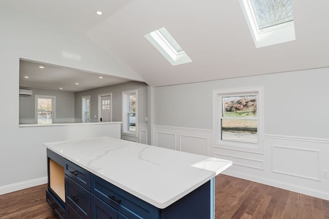 kitchen featuring dark hardwood / wood-style flooring, lofted ceiling with skylight, a center island, and light stone countertops