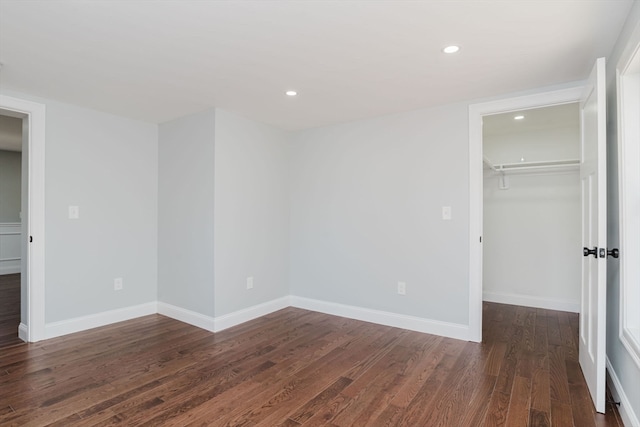 unfurnished bedroom featuring dark hardwood / wood-style flooring, a spacious closet, and a closet