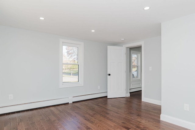 unfurnished room featuring dark hardwood / wood-style flooring and a baseboard heating unit