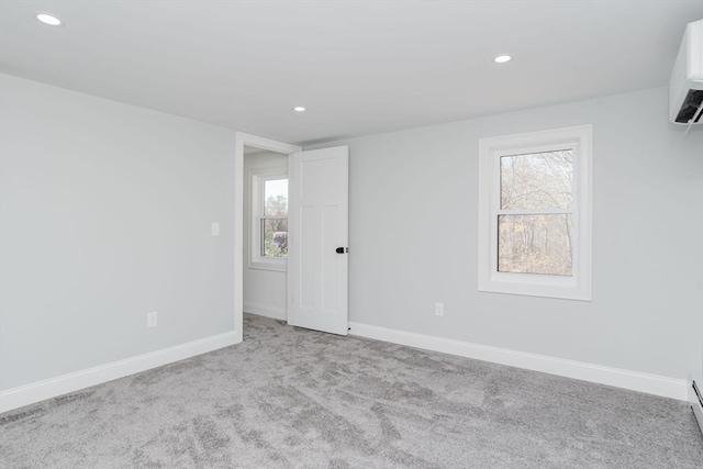 spare room with light colored carpet and a wall unit AC