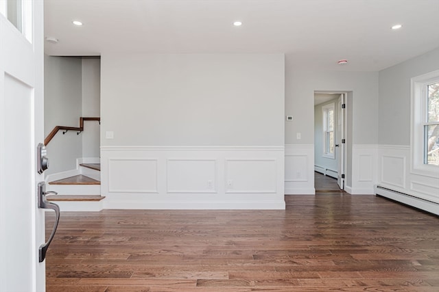 spare room with dark hardwood / wood-style floors and a baseboard heating unit