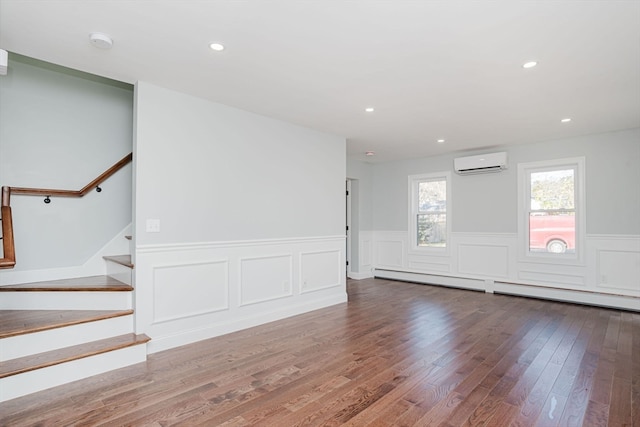 spare room featuring hardwood / wood-style flooring, an AC wall unit, and baseboard heating