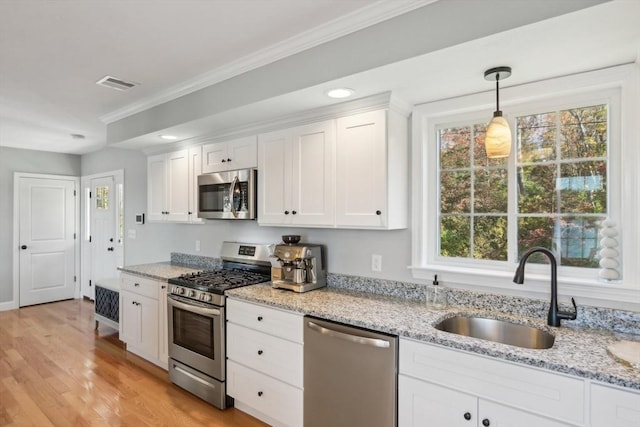 kitchen featuring ornamental molding, a sink, white cabinets, and appliances with stainless steel finishes