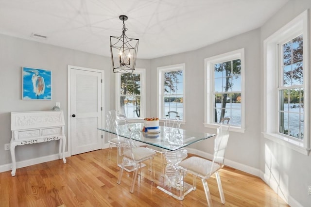 unfurnished dining area with an inviting chandelier, wood finished floors, visible vents, and baseboards