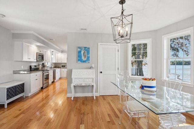 dining space featuring visible vents, a notable chandelier, light wood-style flooring, and plenty of natural light