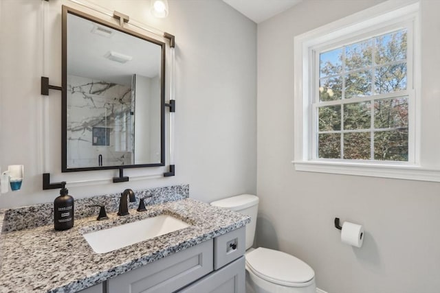 full bathroom with vanity, toilet, baseboards, and a marble finish shower