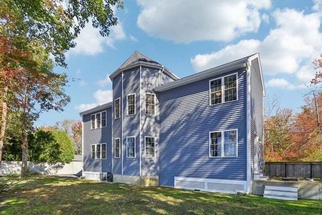 rear view of property featuring fence, cooling unit, and a lawn