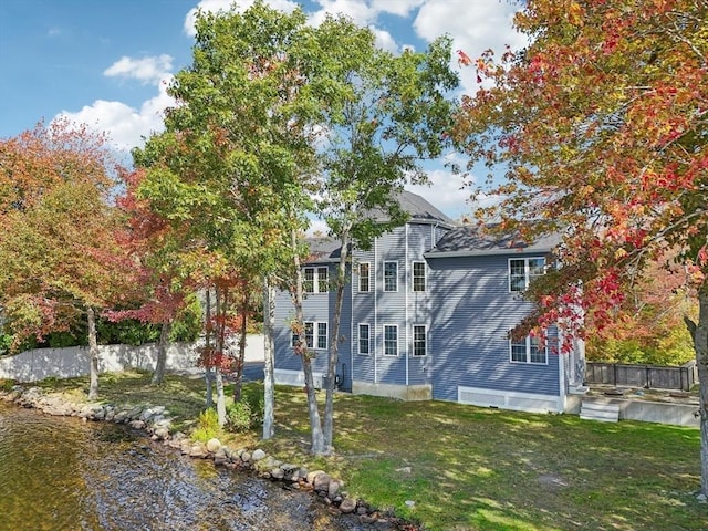 rear view of property with fence and a lawn