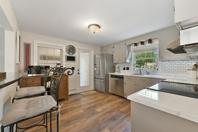 1026 Chandler St, Tewksbury, MA 01876 - kitchen with appliances with stainless steel finishes, backsplash, wood finished floors, light countertops, and wall chimney range hood