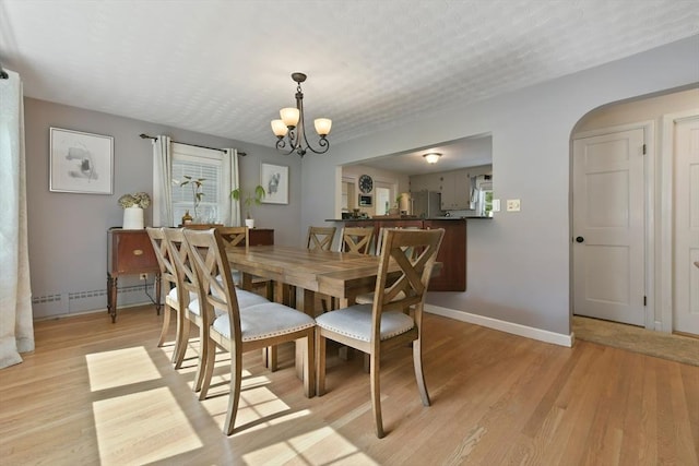 1026 Chandler St, Tewksbury, MA 01876 - dining area with a chandelier, light wood finished floors, arched walkways, and a baseboard radiator