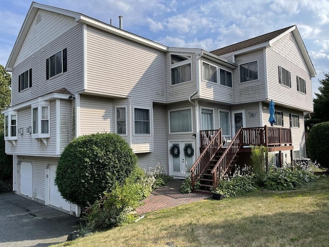 view of front of home featuring a deck, a garage, stairs, driveway, and a front lawn