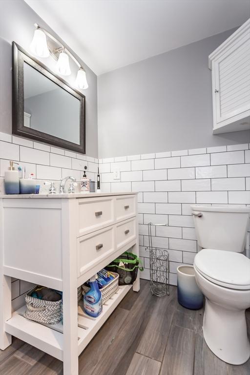 bathroom featuring toilet, tile walls, hardwood / wood-style floors, and vanity