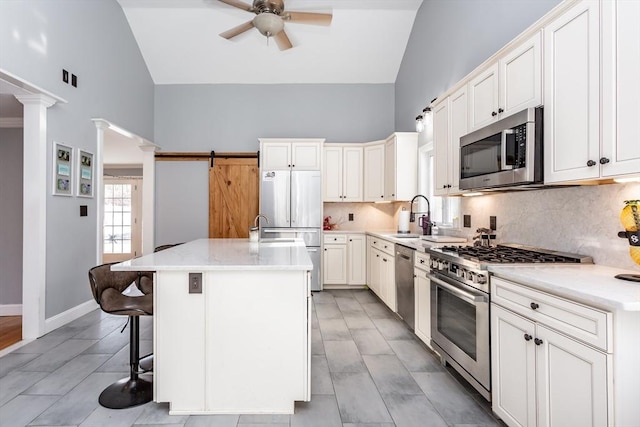 kitchen with a kitchen bar, a center island with sink, stainless steel appliances, decorative backsplash, and sink