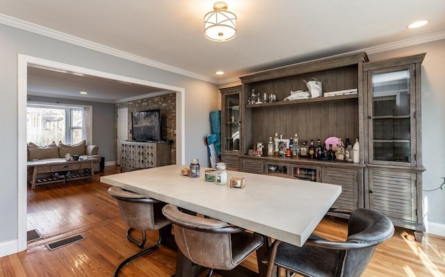 bar featuring crown molding, hardwood / wood-style flooring, and dark brown cabinetry