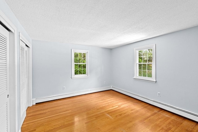91 Observatory Waye, Marshfield, MA 02050 - unfurnished bedroom with wood finished floors, a baseboard radiator, multiple windows, a textured ceiling, and a baseboard heating unit