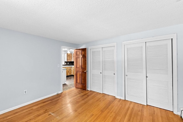 91 Observatory Waye, Marshfield, MA 02050 - unfurnished bedroom featuring two closets, light wood-style flooring, baseboards, and a textured ceiling