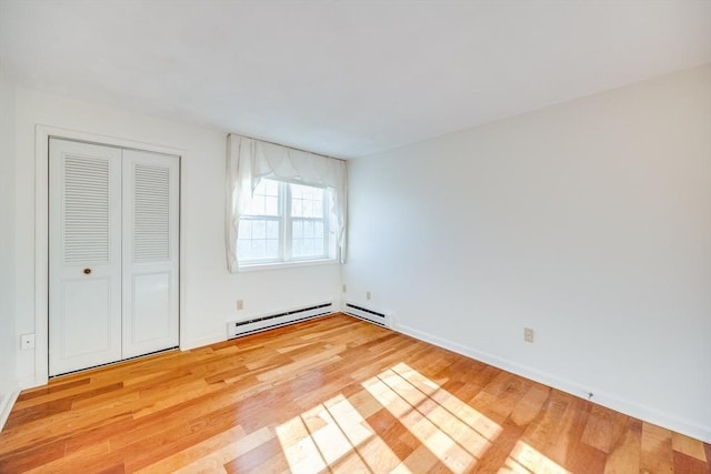 33 Highview Dr Unit 33, Sandwich, MA 02563 - unfurnished bedroom featuring a closet, baseboards, a baseboard heating unit, and light wood-type flooring
