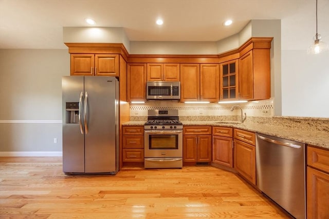 10 Chase Lndg Unit B, Easton, MA 02375 - kitchen with appliances with stainless steel finishes, a sink, brown cabinets, light stone countertops, and backsplash