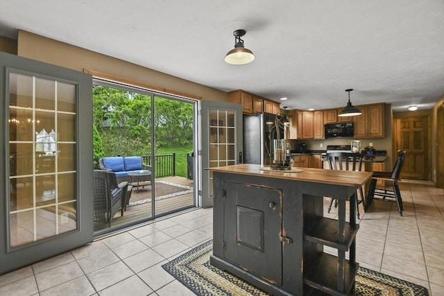 18 Jackson Ave, Rutland, MA 01543 - kitchen with freestanding refrigerator, black microwave, light tile patterned flooring, stove, and brown cabinetry