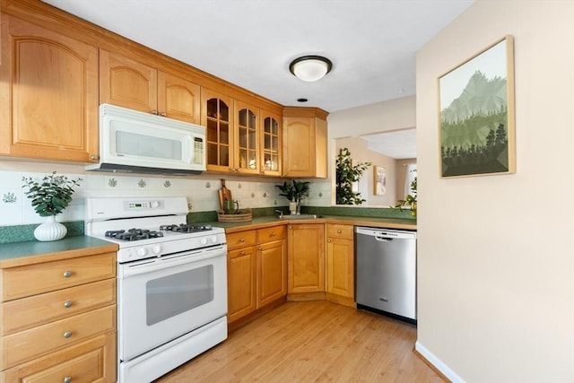 kitchen featuring light wood-type flooring, backsplash, and white appliances