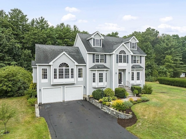 view of front of property featuring aphalt driveway, a front yard, roof with shingles, and a garage