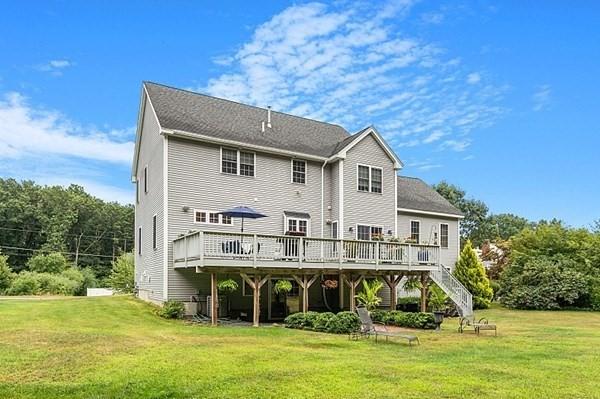 back of house with stairway, a lawn, and a wooden deck