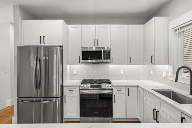50 Cottage St Unit 1, Chelsea, MA 02150 - kitchen featuring appliances with stainless steel finishes, a sink, light stone countertops, white cabinetry, and tasteful backsplash