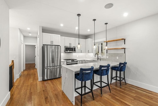 50 Cottage St Unit 1, Chelsea, MA 02150 - kitchen featuring stainless steel appliances, a peninsula, baseboards, tasteful backsplash, and recessed lighting