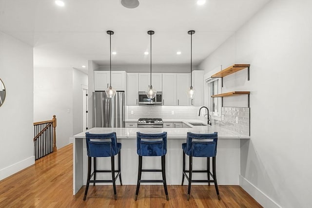 50 Cottage St Unit 1, Chelsea, MA 02150 - kitchen featuring appliances with stainless steel finishes, a sink, a peninsula, light countertops, and tasteful backsplash