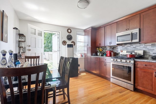 kitchen with backsplash, stainless steel appliances, light wood-style floors, and light countertops