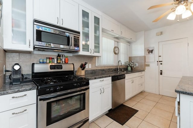 kitchen with a ceiling fan, a sink, light tile patterned floors, white cabinets, and stainless steel appliances