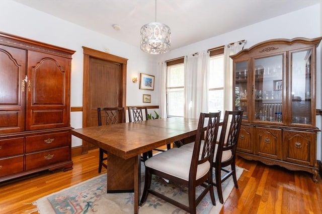 dining space with light wood finished floors and a chandelier
