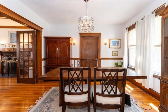 dining space featuring baseboards, an inviting chandelier, and light wood-style floors