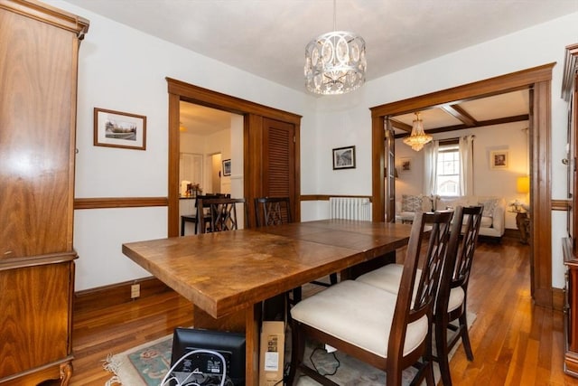 dining room featuring baseboards, dark wood-style flooring, radiator heating unit, and a chandelier