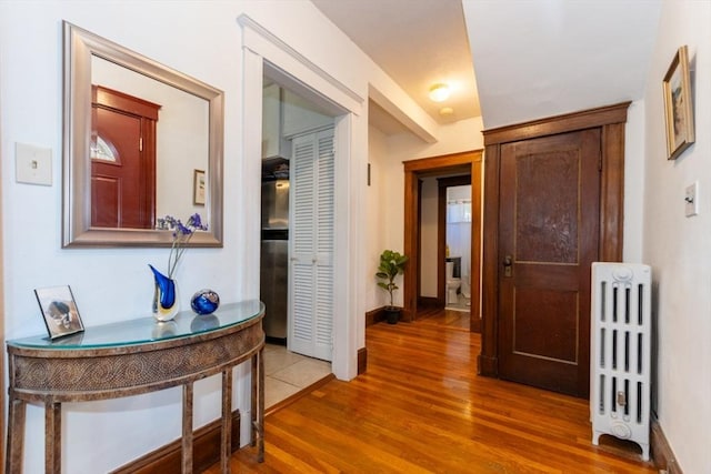 hall featuring wood finished floors, baseboards, and radiator heating unit