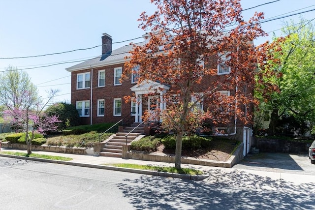 colonial inspired home with a chimney and brick siding
