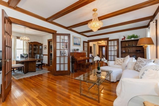 living area featuring a notable chandelier, ornamental molding, beam ceiling, and hardwood / wood-style flooring