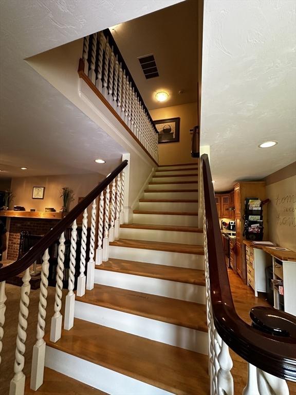 staircase with wood finished floors and recessed lighting