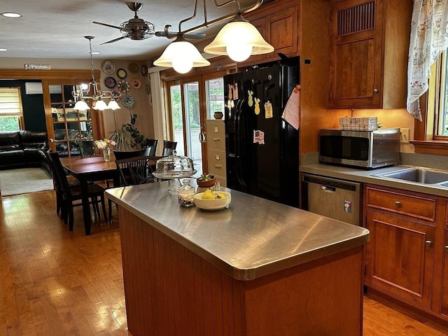 kitchen with stainless steel countertops, stainless steel appliances, a kitchen island, brown cabinets, and recessed lighting