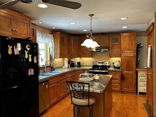 kitchen with appliances with stainless steel finishes, under cabinet range hood, a sink, brown cabinets, and recessed lighting