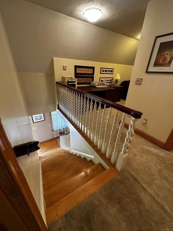 staircase featuring lofted ceiling, baseboards, and carpet flooring