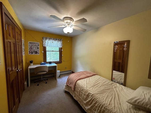 bedroom featuring a baseboard radiator, carpet, an office area, and a closet