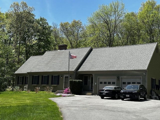 view of front of house with asphalt driveway, a garage, a chimney, a front lawn, and a shingled roof