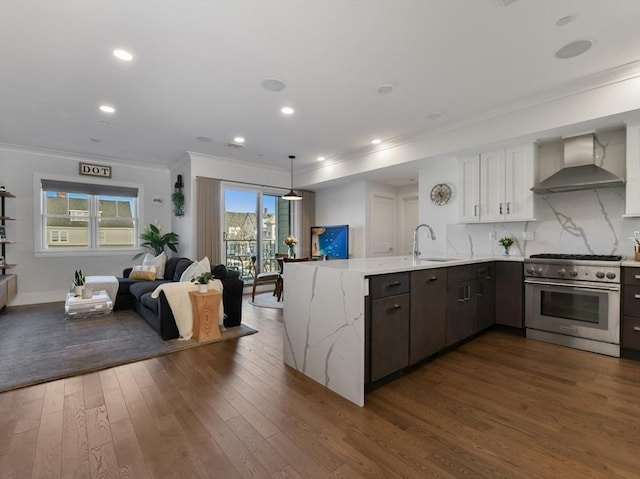 kitchen featuring sink, high end stainless steel range oven, white cabinetry, wall chimney range hood, and kitchen peninsula