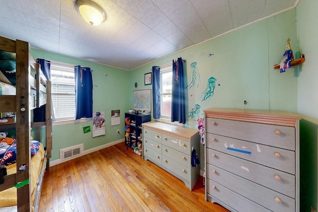 bedroom with visible vents, light wood-style flooring, baseboards, and multiple windows