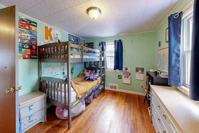 bedroom featuring wood-type flooring, visible vents, and baseboards