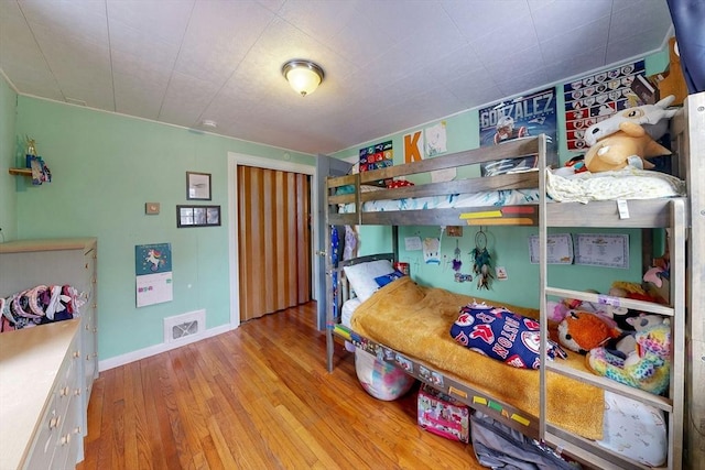 bedroom featuring visible vents, baseboards, and wood finished floors